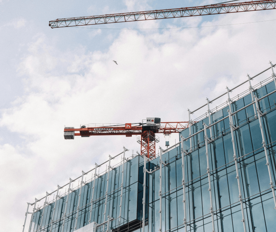 Picture of a scaffolded skyscraper. Contains two machines similar to construction cranes to move heavy materials.