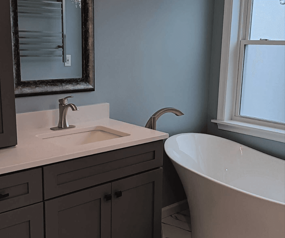 A previous bathroom renovation that BiiLT was chosen for. A dark brown vanity, white tub, and white sink are all present within the picture. The floor looks to be a marble pattern with black and white.