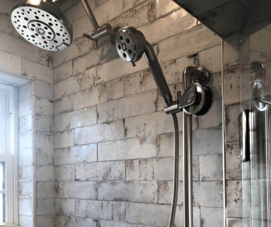 A close up of a tiled bathroom shower that BiiLT completed. A lovely dark grey tile with a silver mixing valve and silver shower heads.
