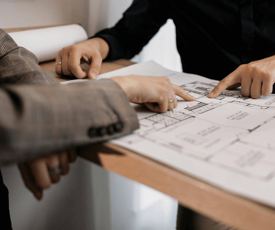 Hands pointing to different sections on a blueprint. The blueprint is a residential home build.