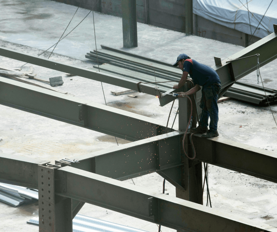 A steel frame being worked on by a professional. It appears that the person is cutting the overlaying edge of the steel off.